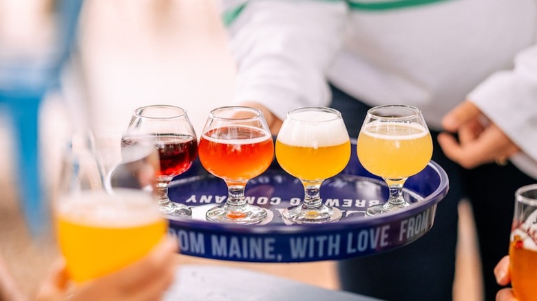 A woman holding a flight of beer on a blue tray