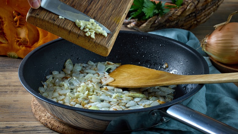 Adding chopped garlic to a frying pan