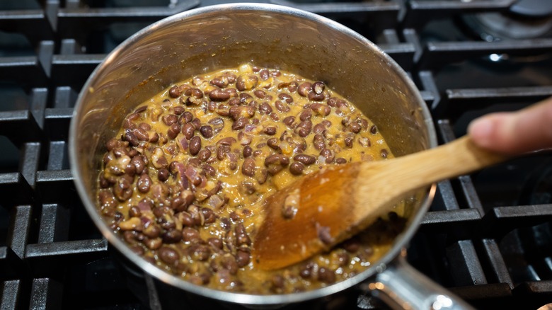 Stirring beans and sauce in a frying pan