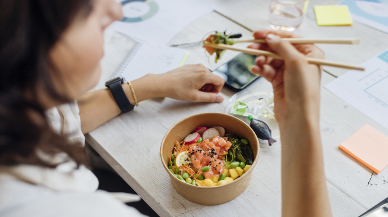 Person eating poke bowl at desk