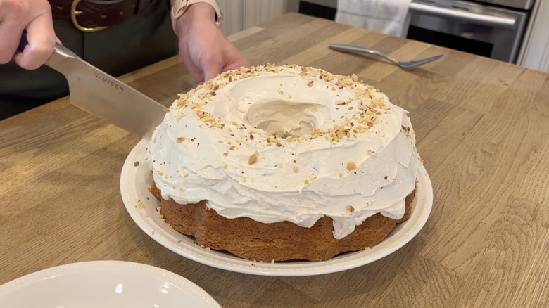 up close of woman slicing white almond cake