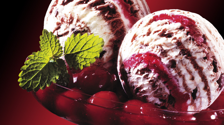 two scoops of cherry vanilla ice cream in glass container