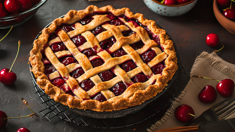 cherries surrounding cherry pies on dark table
