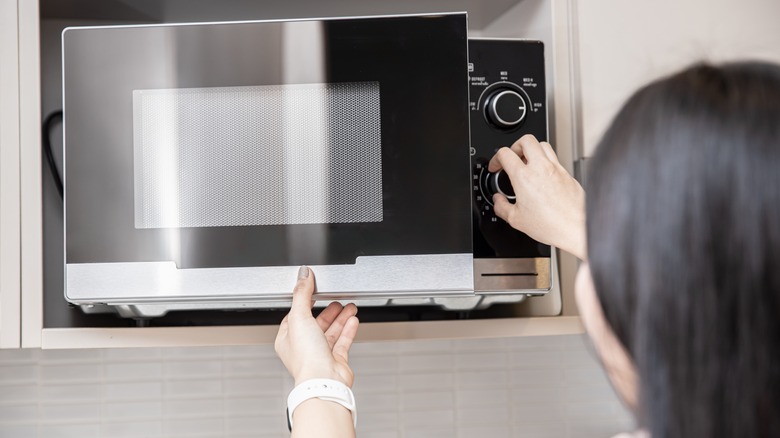 Woman opening microwave door