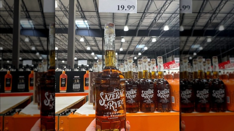 Person holding a bottle of Sazerac Rye whiskey in front of shelf