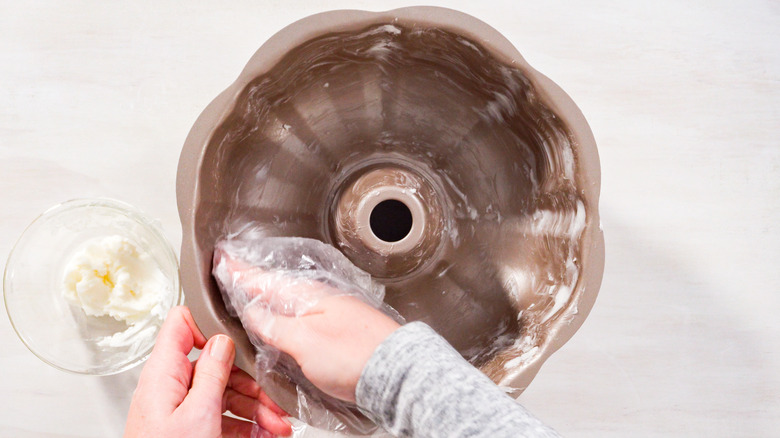 Person greasing cake pan with butter