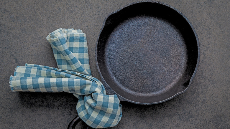 Empty cast iron pan with dishtowel around its handle