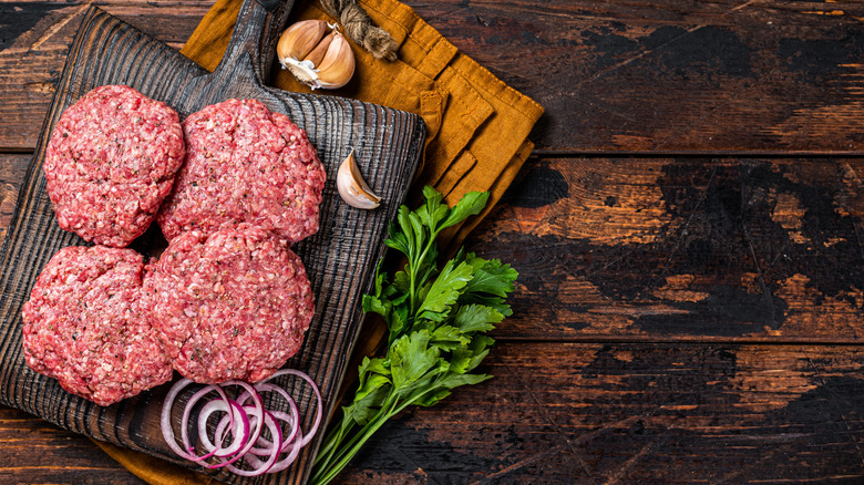 Burger patties on wooden board