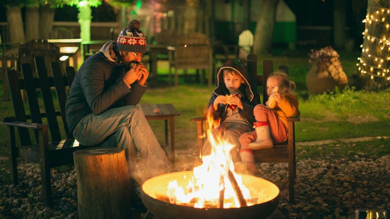 Family eating around camp fire