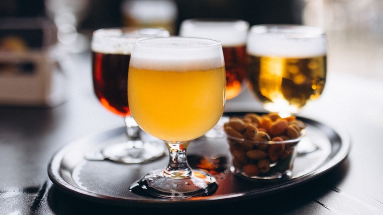 Glasses of beer on a serving tray with nuts