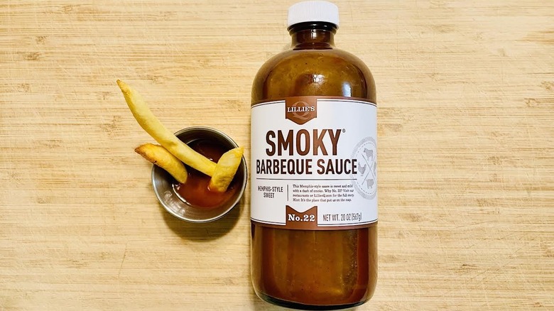 Bottle of Lillie's Q Memphis-Style Sweet Smoky BBQ Sauce with full ramekinholding fries