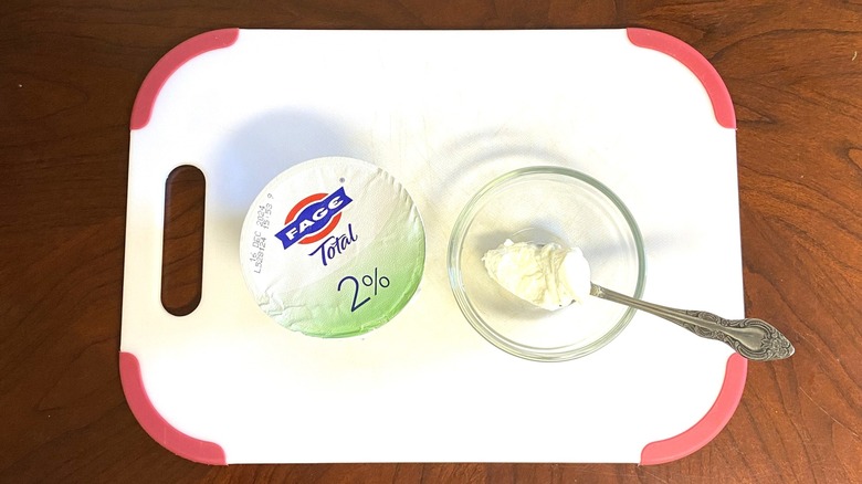 Fage 2% Greek yogurt is shown on a table beside a sample