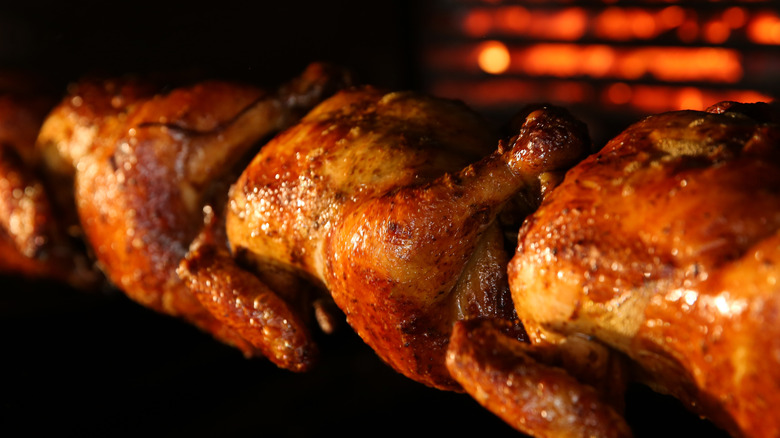 Rotisserie chickens grilling on spit