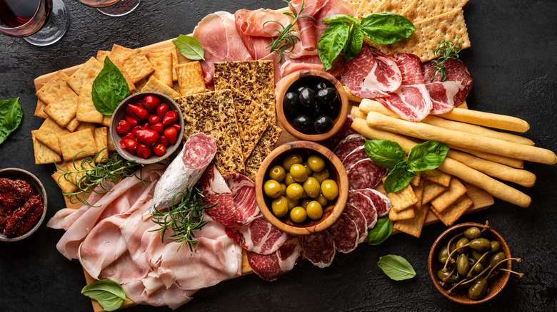 Charcuterie board with meat, pickles, and crackers