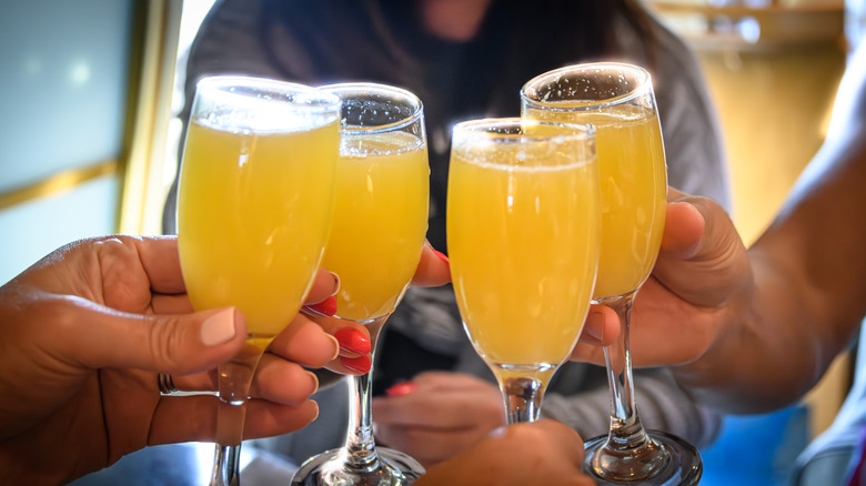 Holding four mimosa glasses