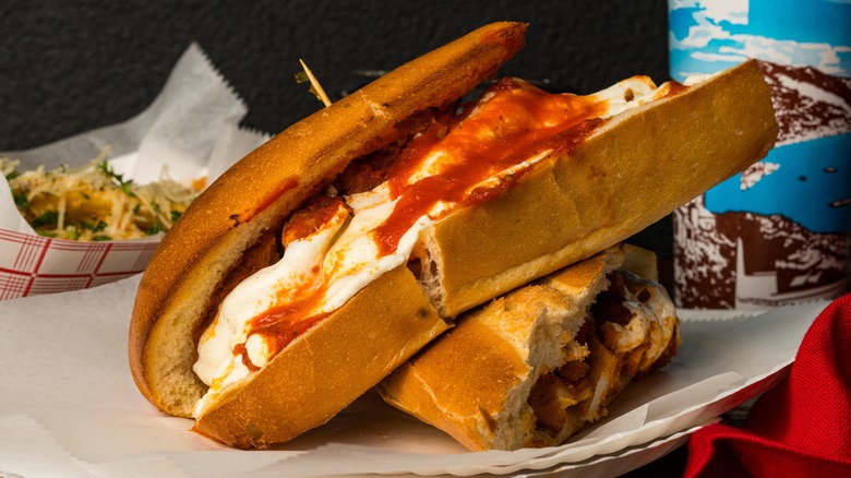A chicken Parmesan sandwich on paper plate.