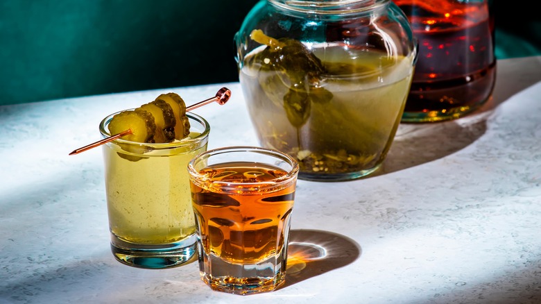 Glasses and jars of pickle juice and amber liquor