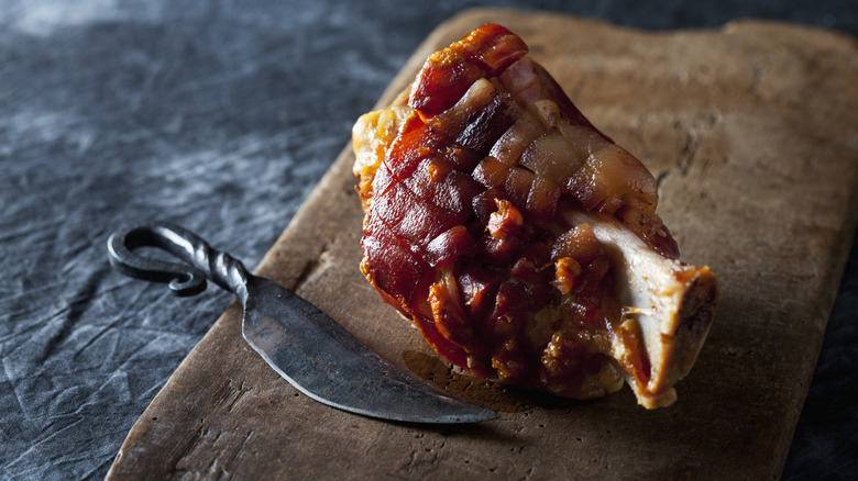 A cooked ham hock on a cutting board