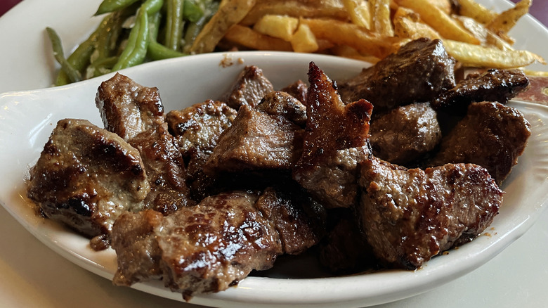 Steak tips on a plate with green beans and french fries