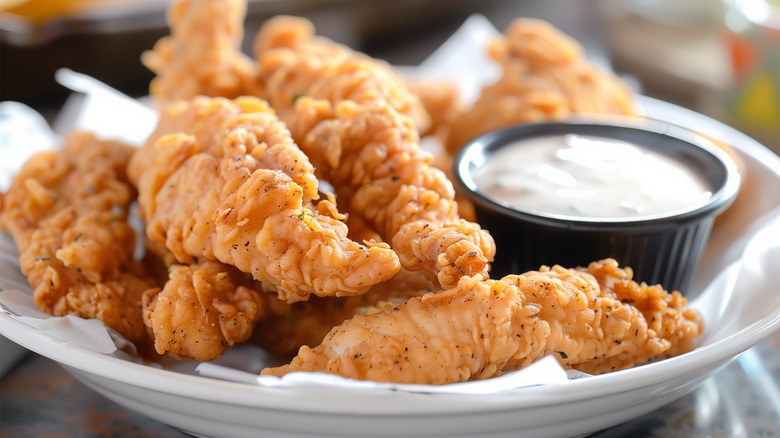 Plate of fried chicken tenders with creamy dipping sauce