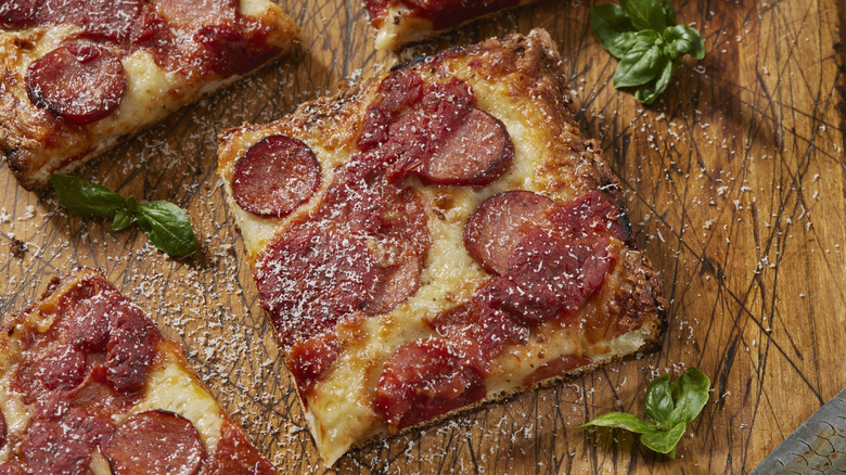 Slices of Detroit-style pepperoni pizza on a wooden cutting board