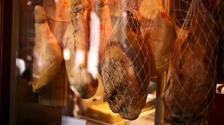 Whole hams hanging in a deli