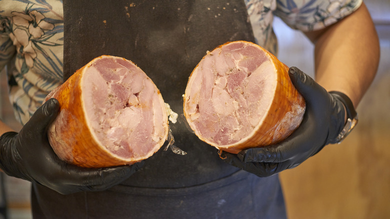 man holding two halves of a ham