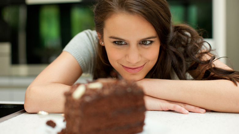 woman looks at chocolate cake 
