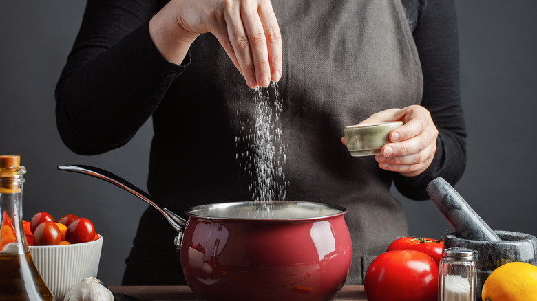 Chef adds salt to a pot