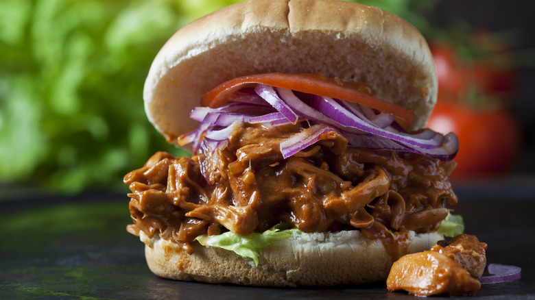 A jackfruit BBQ sandwich with lettuce, tomato, and onion on a bun