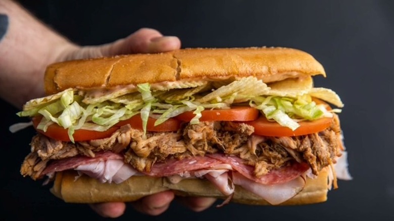 Hand holding massive pulled pork sandwich