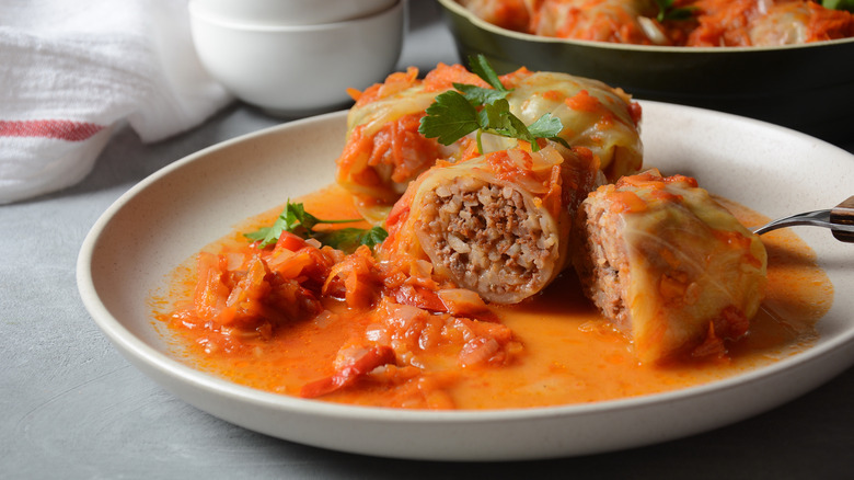 plate with cabbage rolls topped with peppers and herbs