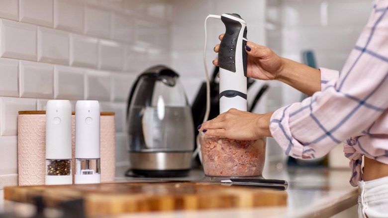 Woman grinding meat in food processor