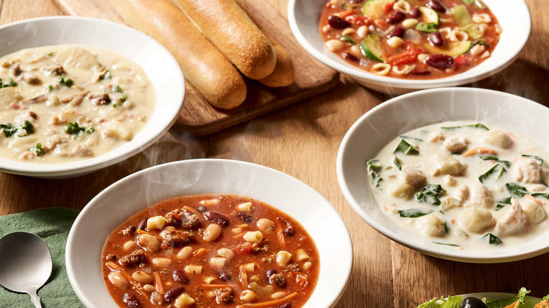 Various Olive Garden Soups displayed on table with breadsticks