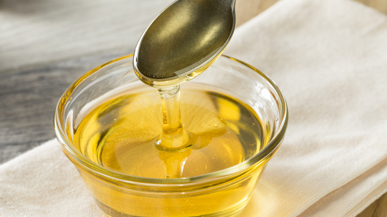 spoon scooping agave nectar in glass bowl