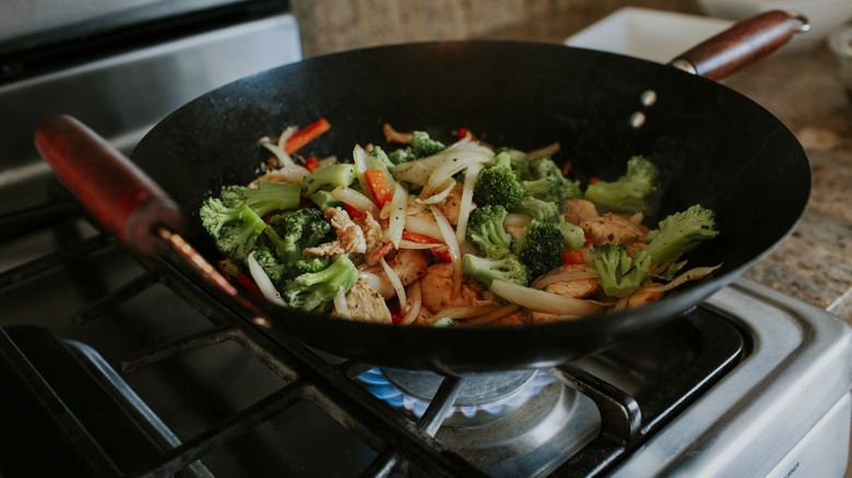 Stir-fry vegetables and chicken in a wok on the stove