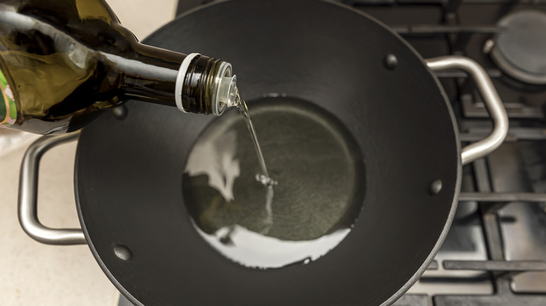 Pouring oil into a wok positioned on the stove