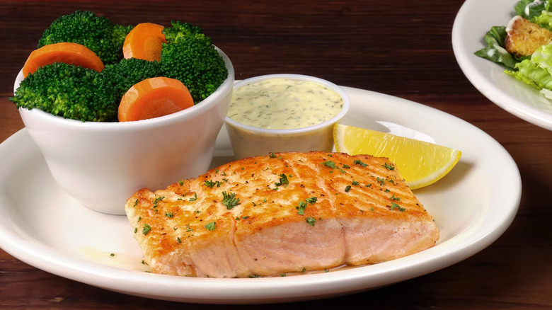 A plate of grilled salmon with a bowl of broccoli and carrots from Texas Roadhouse