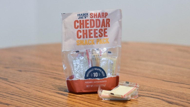 A bag of Trader's Joes sharp cheddar cheese packs sit on a wooden table.