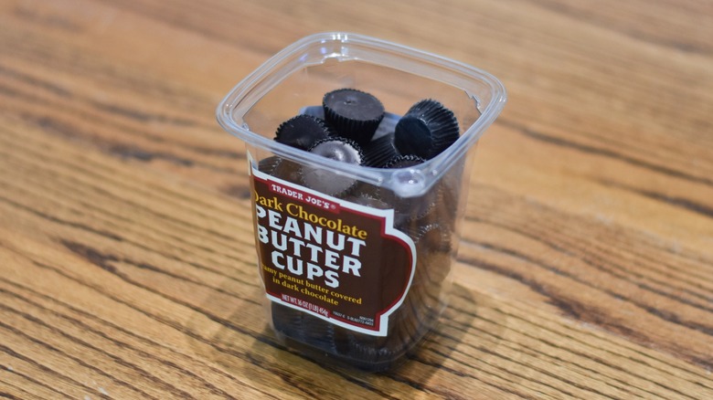 A container of Trader Joe's dark chocolate peanut butter cups sits on a wooden table.