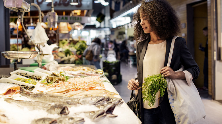 Woman shopping for fresh fish at supermarket