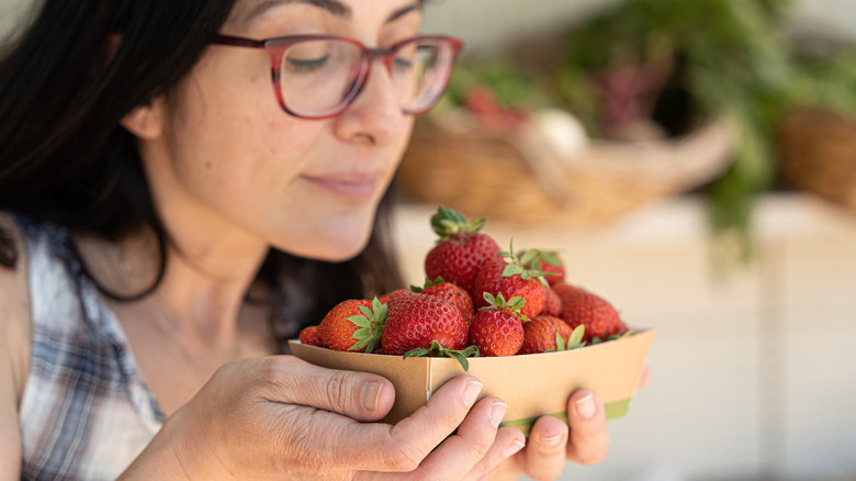 Person smelling bowl of strawberries