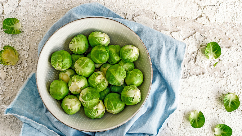 A bowl of fresh Brussels sprouts on top of a kitchen towel