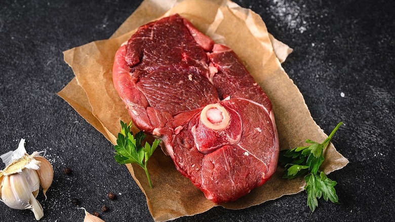 Uncooked lamb steak with parsley on squares of brown parchment paper
