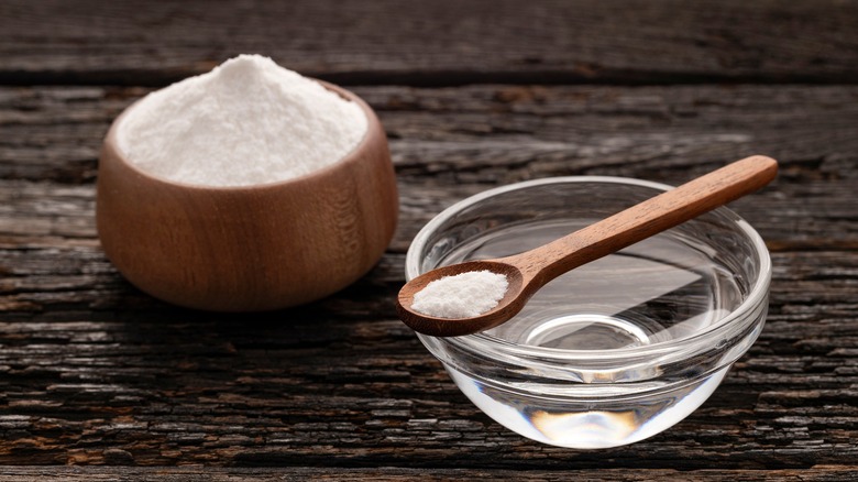 A wooden bowl of baking soda and a small bowl of water