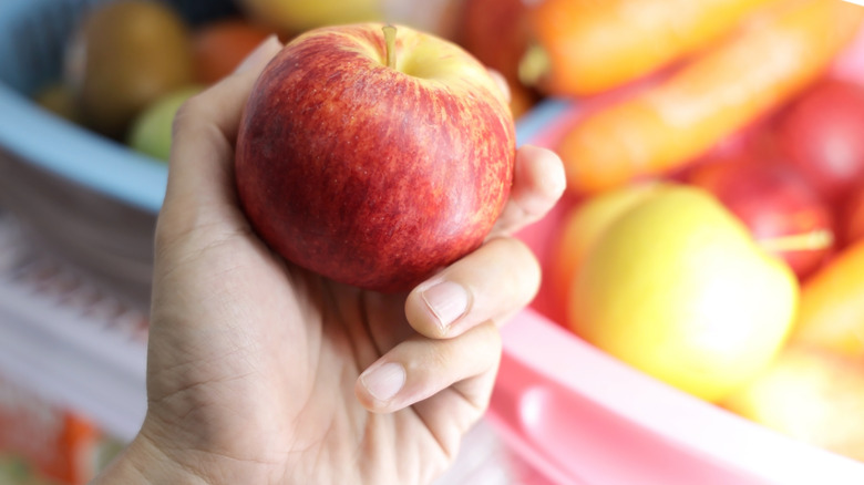 hand pulling apple from fridge
