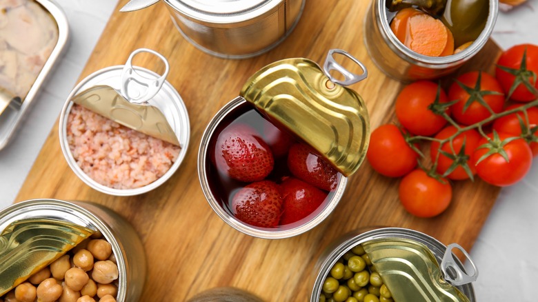 Open cans on wooden cutting board