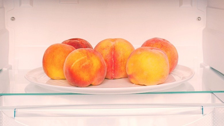 whole peaches on plate in fridge