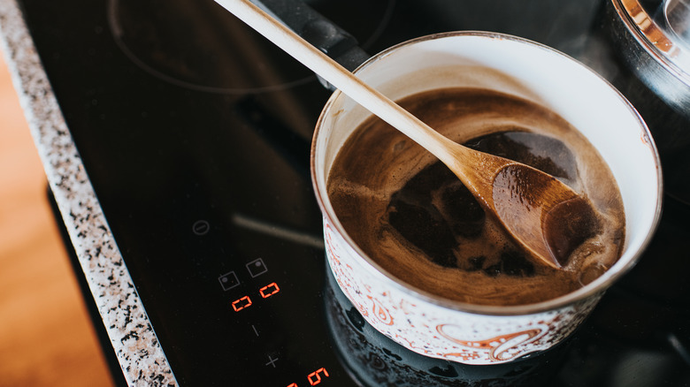 Wooden spoon resting on a pot of gravy cooking on a stovetop