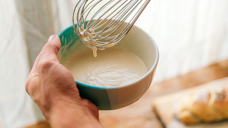 Person whisking mayonnaise in a bowl